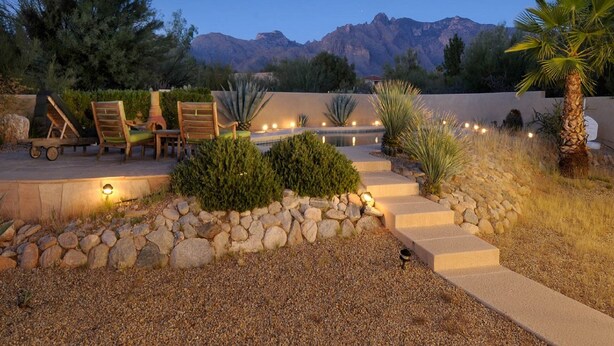 A patio area with outdoor seating, a stone wall, and a view of mountains. - PRIVATE CONTEMPORARY HOME WITH BREATHTAKING MOUNTAIN VIEWS (Tucson)