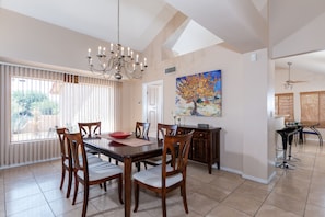 A dining area with a wooden table and chairs, a chandelier, and a painting on the wall. - PRIVATE CONTEMPORARY HOME WITH BREATHTAKING MOUNTAIN VIEWS (Tucson)