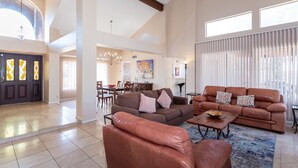 A spacious living room with a brown leather sofa set, a coffee table, and a dining area in the background. - PRIVATE CONTEMPORARY HOME WITH BREATHTAKING MOUNTAIN VIEWS (Tucson)
