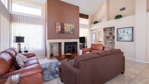A spacious living room with a fireplace, leather sofas, and a large window with blinds. - PRIVATE CONTEMPORARY HOME WITH BREATHTAKING MOUNTAIN VIEWS (Tucson)