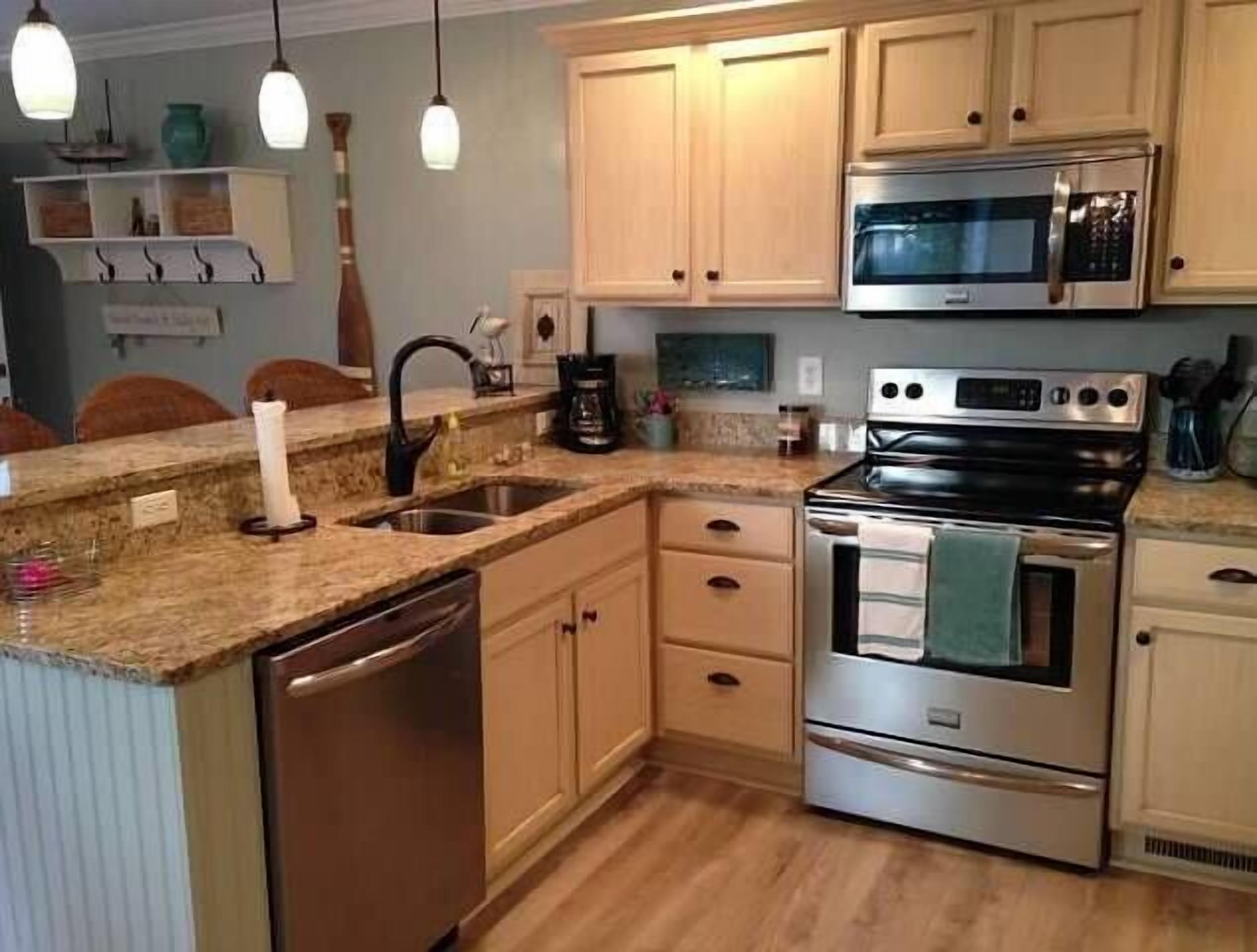 A kitchen with wooden cabinets, a stainless steel dishwasher, a double oven, and a microwave.