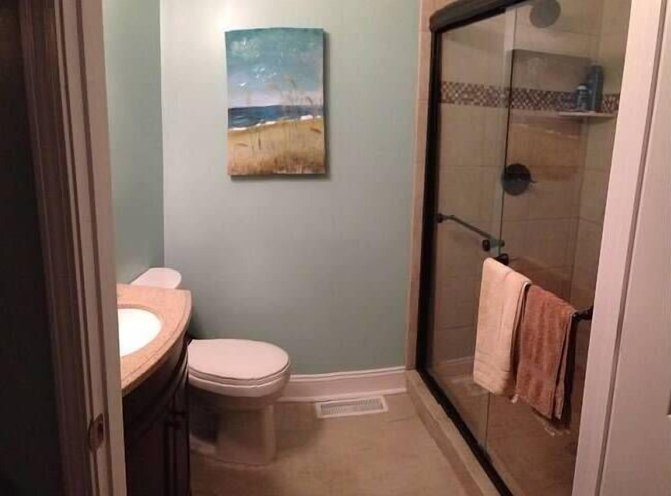 Een badkamer met toilet, wastafel en een douchecabine met glazen wanden.