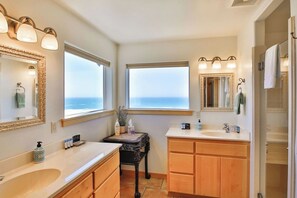 Un baño con dos lavamanos, tocador, espejo y ventana con vistas.
