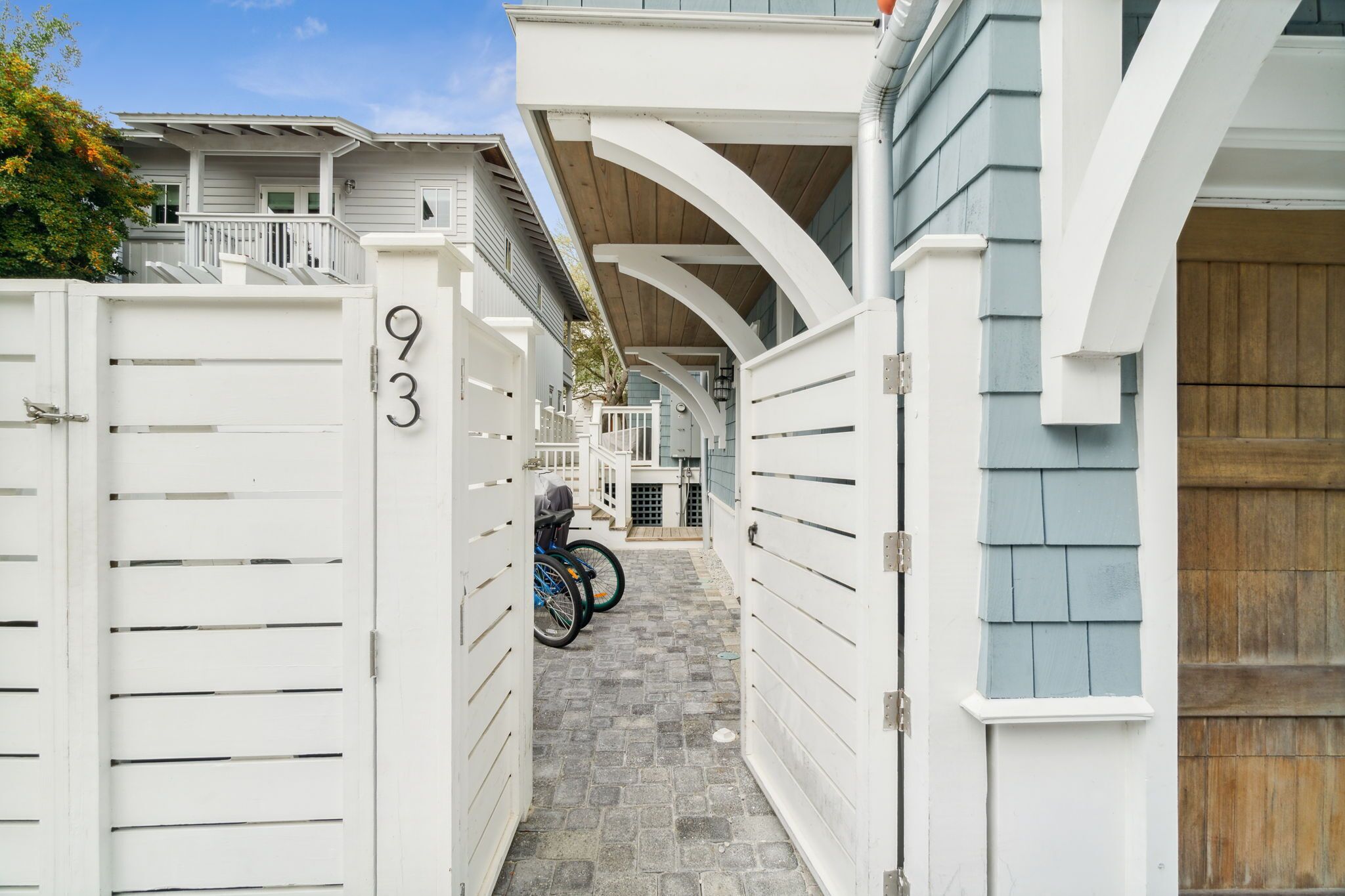 A narrow, gated pathway leading to a house with a number '93' on the gate.