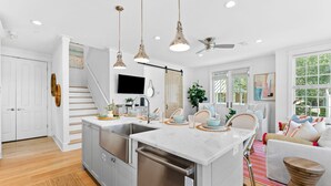 Una cocina moderna con una isla central, electrodomésticos de acero inoxidable e iluminación colgante.