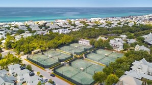 Zona residencial con varias canchas de tenis rodeada de casas y vegetación.