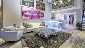 A spacious living area with a glass coffee table, white sofas, and abstract art on the walls. - Stunning Remodel 4 BR/3 BA Downtown ,Gaslamp, Petco, Convention Center (San Diego)