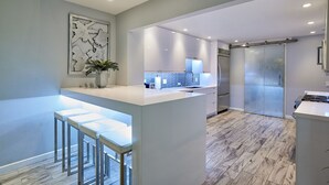 A modern kitchen with a central island, bar stools, a refrigerator, and a backsplash with a geometric pattern. - Stunning Remodel 4 BR/3 BA Downtown ,Gaslamp, Petco, Convention Center (San Diego)