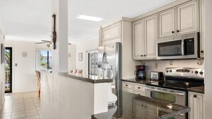 Una cocina moderna con armarios blancos, electrodomésticos de acero inoxidable y encimera de granito.