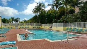 Une piscine avec des chaises longues et une terrasse en briques.