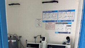 Une buanderie équipée de deux machines à laver et d’un chauffe-eau, ainsi que de panneaux explicatifs affichés au mur.