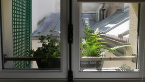 A window with a view of a balcony, a potted plant, and a green metal fence. - LATIN QUARTER, PARIS VIEW, 30–60 days ahead? Ask for a private offer. C5-VAs (Paris)