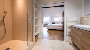 A modern bathroom with a glass shower enclosure, a wooden vanity, and a bed in the adjacent room. - LATIN QUARTER, PARIS VIEW, 30–60 days ahead? Ask for a private offer. C5-VAs (Paris)