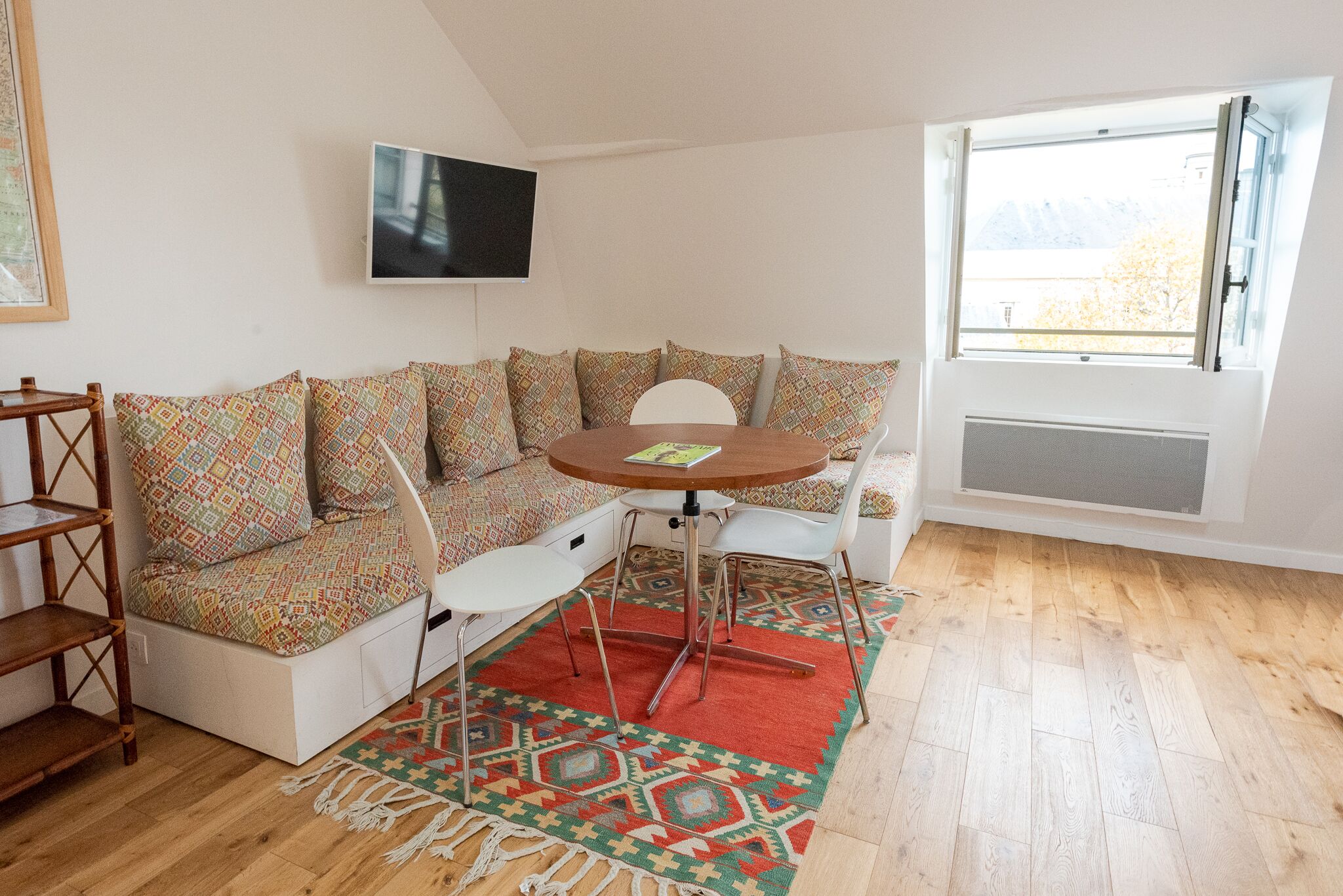 Ein gemütliches Zimmer mit einer Couch, einem kleinen Tisch und einem an der Wand befestigten Fernseher.