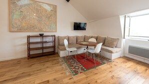 A cozy loft bedroom with a large map, a TV, a wooden floor, a patterned rug, and a built-in seating area. - LATIN QUARTER, PARIS VIEW, 30–60 days ahead? Ask for a private offer. C5-VAs (Paris)