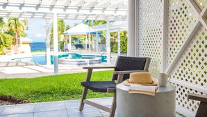 Un patio con piscina, zona de estar cubierta y vista al océano.