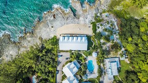 Vista aérea de una propiedad costera con un edificio grande, una piscina y follaje circundante.