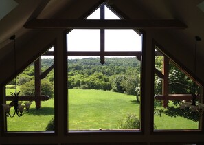 Enjoy a serene view of the lush landscape from the large window, framed by wooden beams and a chandelier.