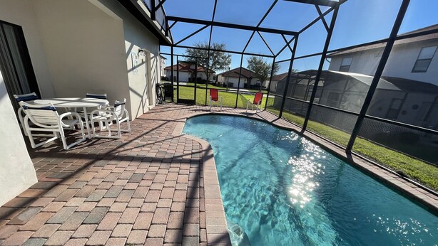 A swimming pool with a brick patio and outdoor seating area. - Gorgeous Pool Home, Big Yard, 6 miles to Disney, Gated Resort, Amenities for All (Clermont)