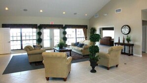 A spacious lobby with beige armchairs, a coffee table, and potted plants. - Gorgeous Pool Home, Big Yard, 6 miles to Disney, Gated Resort, Amenities for All (Clermont)