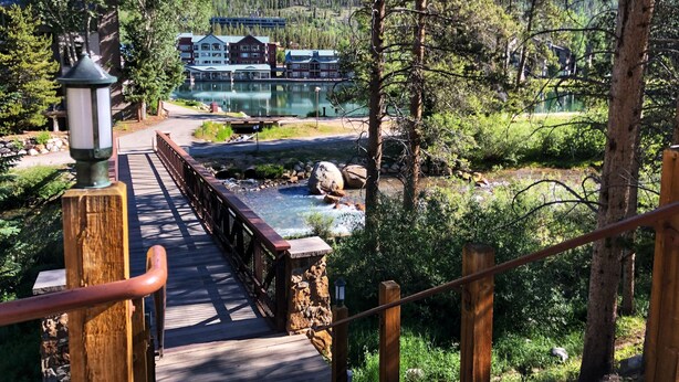 A wooden bridge leading to a building with a view of a lake and forest. - Mountain-chic retreat - sleeps 10  - room for everyone (Keystone)