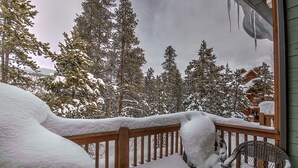 A snow-covered deck with a wooden railing and a wicker chair. - Mountain-chic retreat - sleeps 10  - room for everyone (Keystone)