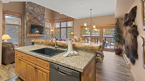 A spacious kitchen with granite countertops, a dishwasher, and a stone accent wall. - Mountain-chic retreat - sleeps 10  - room for everyone (Keystone)