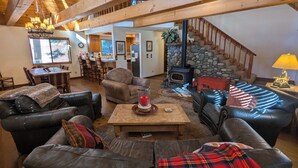 A cozy living room with leather sofas, a wooden coffee table, and a stone fireplace.