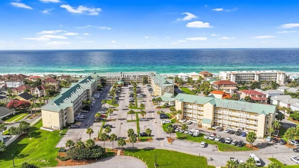 Un complejo hotelero con varias edificaciones, estacionamiento y vista al océano.