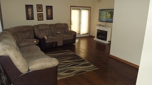 Una sala de estar con un sofá modular, una chimenea y cuadros enmarcados en la pared.