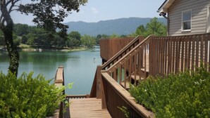 Una terraza de madera que da a un río, con vistas a montañas al fondo.