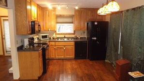 Una cocina con armarios de madera, microondas, lavaplatos y refrigerador.