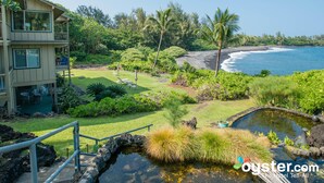 A hotel with a pool, a lawn, and a view of the ocean.