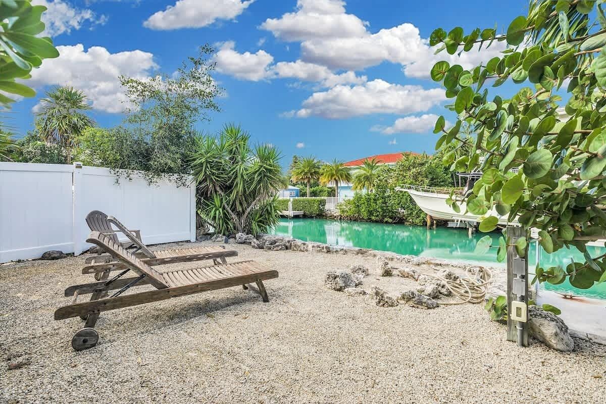 A poolside area with lounge chairs, a pool, and surrounding greenery.