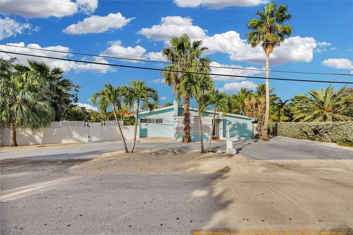 A street with palm trees, a blue building, and a clear sky.