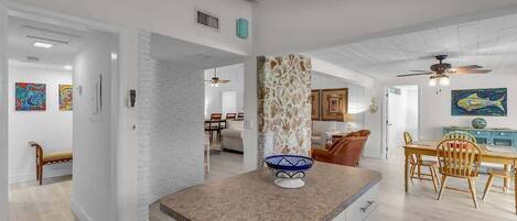 Una cocina moderna con encimera de granito, un pilar de piedra y un comedor con sillas de madera y una mesa.