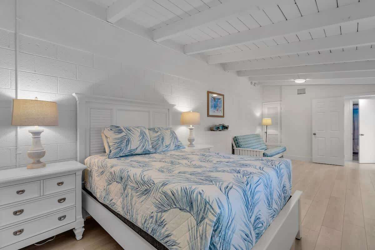 A bedroom with a bed, bedside tables, a chair, and a door.