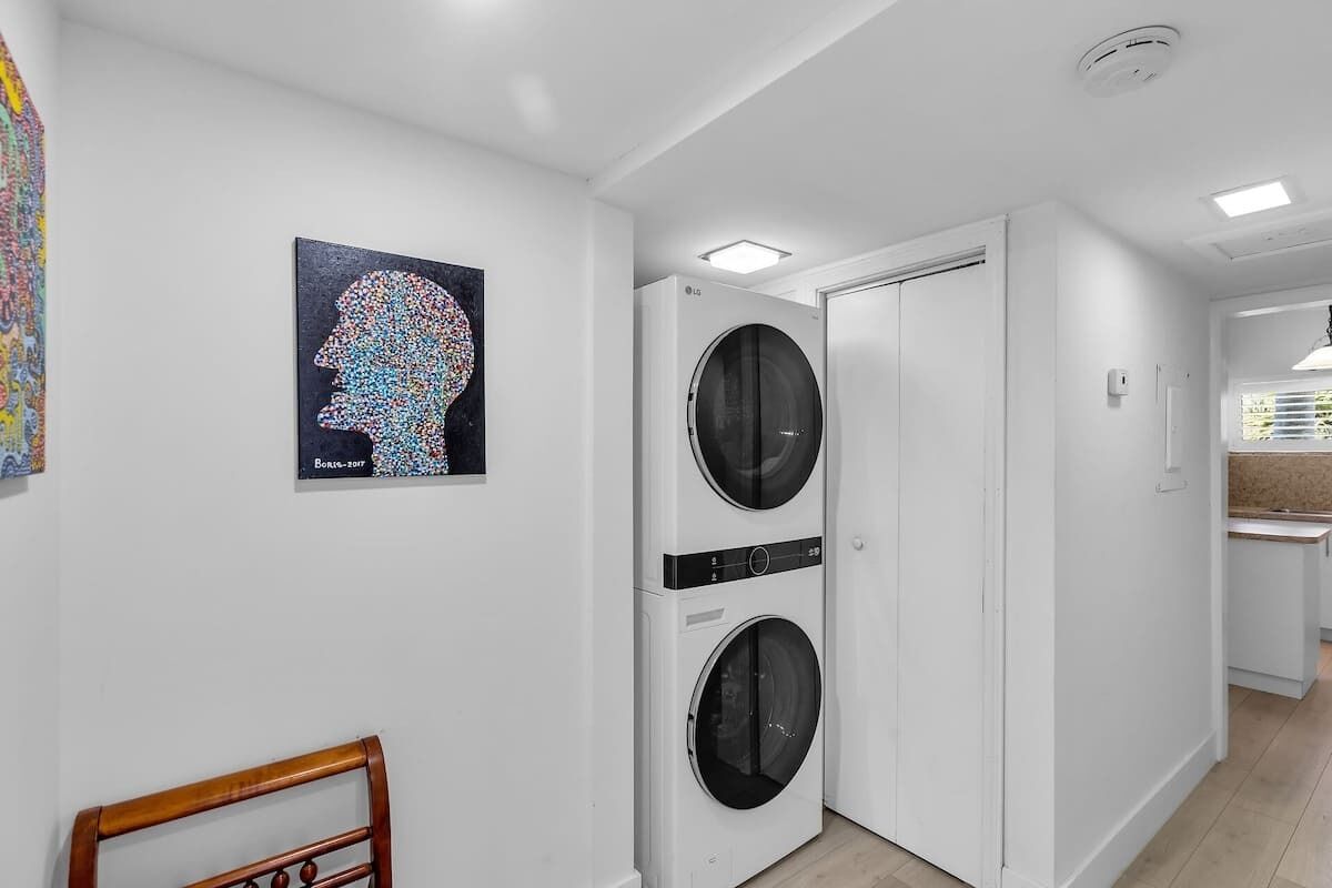 A laundry room with two front-loading washing machines, a wooden chair, and a wall-mounted artwork.