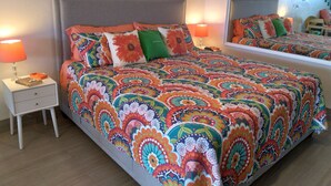 A bedroom with a colorful bedspread, two bedside tables with lamps, a mirror, and a wall with a motivational quote. - IMMACULATE! WASTE NO TIME GETTING TO THE BEACH! (St. Thomas)