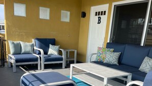 Un espace extérieur aménagé avec un canapé bleu, deux fauteuils et une petite table.