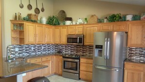A modern kitchen with wooden cabinets, stainless steel appliances, and a tiled backsplash.