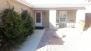 A house with a front door, a small patio with a brick pathway, and a large potted plant.