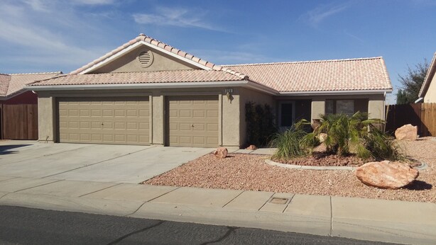 A two-story house with a garage, a covered driveway, and a landscaped front yard with rocks and plants.