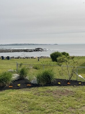 A coastal view with a grassy area, a fence, and a body of water. - Beautiful ocean views & walking distance to the beach. (York)
