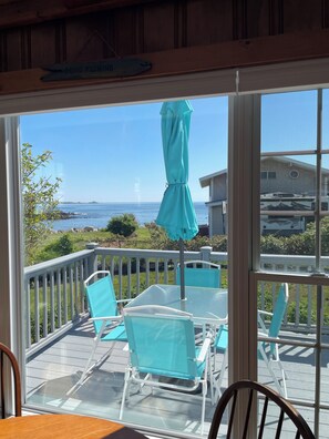 A deck with chairs and a table, overlooking a body of water and a distant shoreline. - Beautiful ocean views & walking distance to the beach. (York)