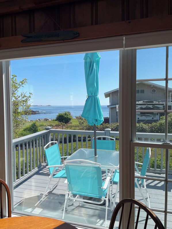A deck with chairs and a table, overlooking a body of water and a distant shoreline. - Beautiful ocean views & walking distance to the beach. (York)