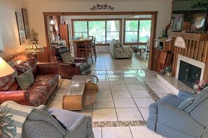 A spacious living room with a fireplace, leather sofas, a coffee table, and a dining area with chairs.