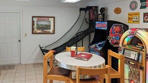 Une pièce avec une petite table, des chaises, un toboggan et un juke-box.