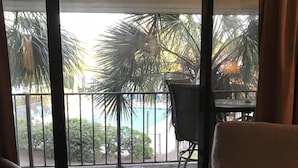 Een kamer met uitzicht op een zwembad en palmbomen door grote ramen.