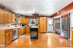 Kitchen features a central island, stainless steel appliances, and a window above the sink.